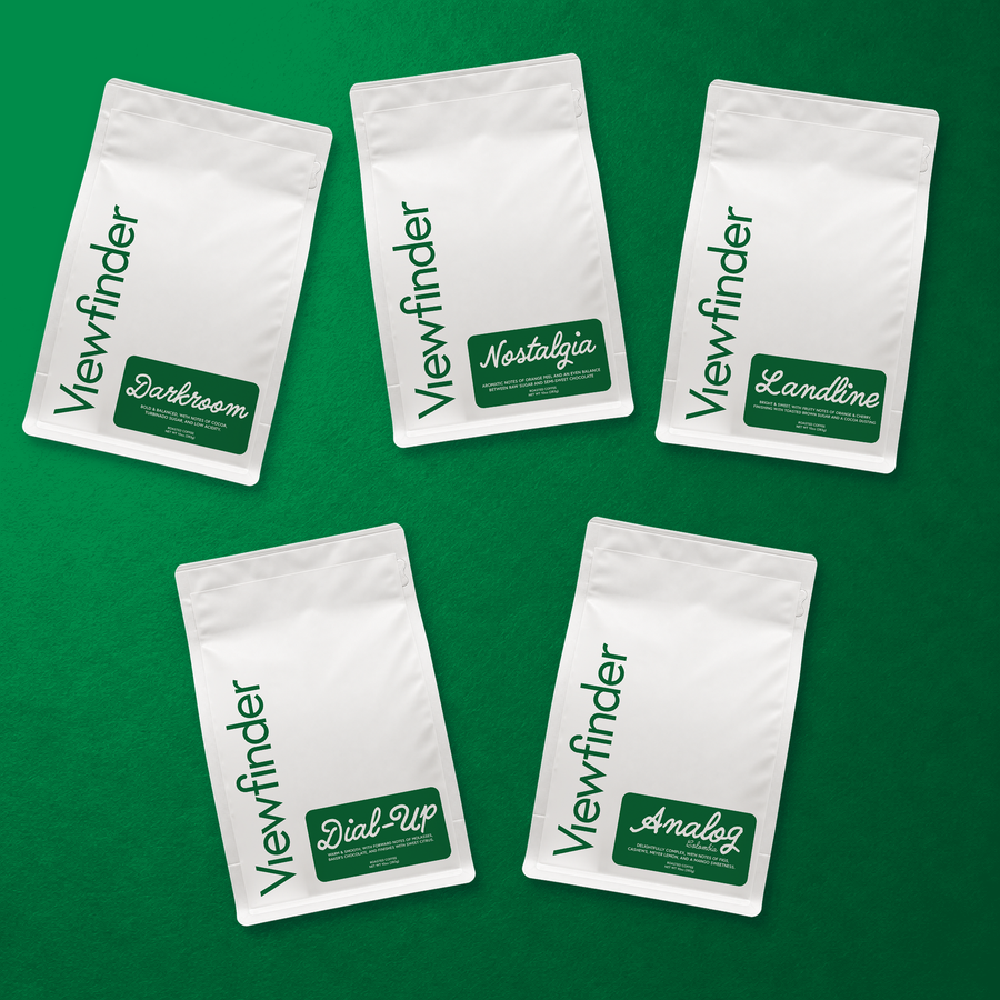 Five Viewfinder Essentials coffee bags: Darkroom, Nostalgia, Landline, Dial-Up, and Analog, arranged on a green background
